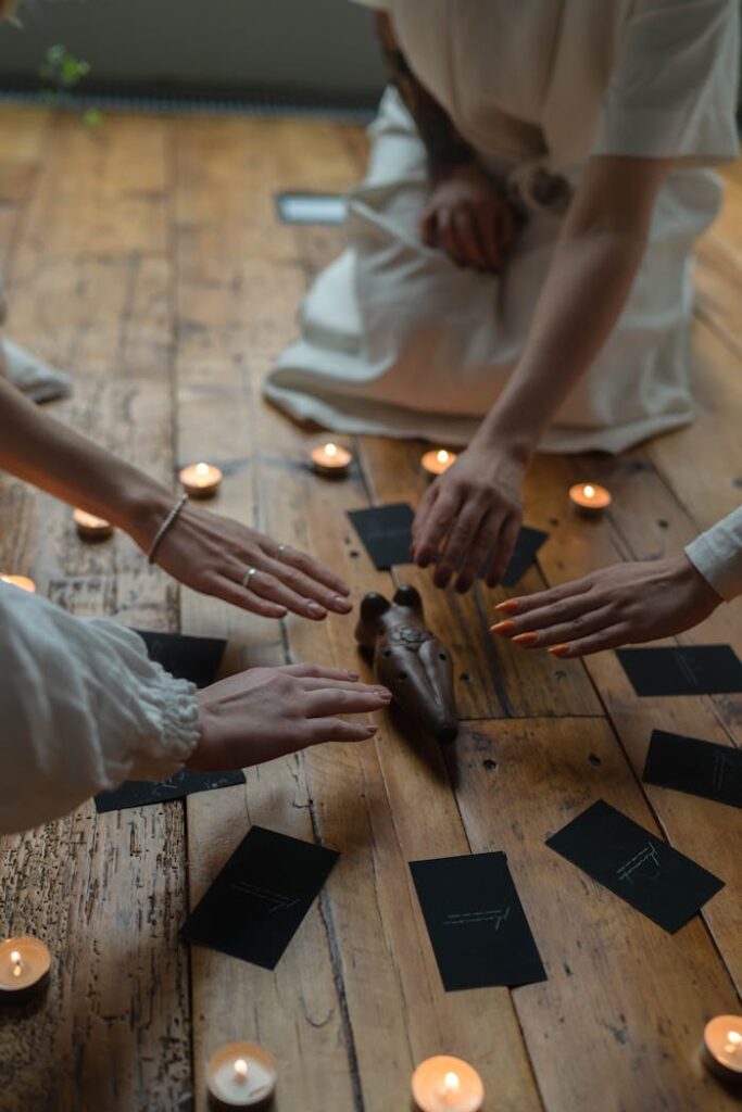 Women gather around candles and cards in a spiritual ritual indoors.
